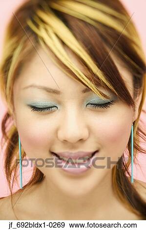 Stock Photo - Young woman smiling with her eyes closed. Fotosearch