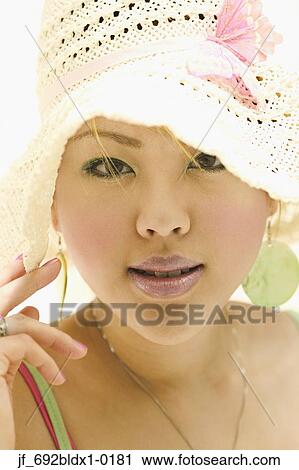 Stock Image - Young woman wearing a hat looking at camera. Fotosearch
