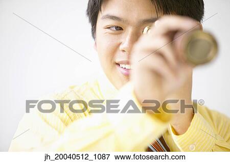 Businessman looking through a telescope smiling View Large Photo Image Stock Photo - Businessman looking through a telescope smiling. Fotosearch
