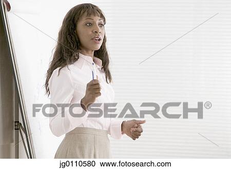 Businesswoman standing at an office presentation talking View Large Photo Image Stock Image - Businesswoman standing at an office presentation talking. Fotosearch