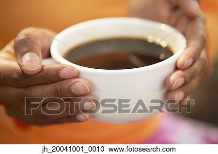 Close-up of a young woman holding a cup of coffee View Large Photo Image Stock Image - Close-up of a young woman holding a cup of coffee. Fotosearch