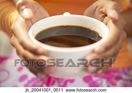 Close-up of a young woman holding a cup of coffee View Large Photo Image Stock Image - Close-up of a young woman holding a cup of coffee. Fotosearch