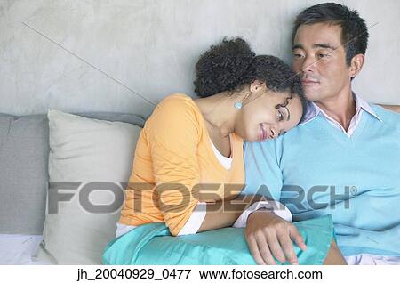 Couple relaxing on a couch close to each other View Large Photo Image Stock Photo - Couple relaxing on a couch close to each other. Fotosearch