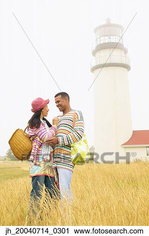 Stock Image - Couple standing in a field looking at each other. Fotosearch
