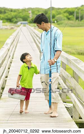 Father and son walking on a pier holding fishing gear View Large Photo Image Stock Image - Father and son walking on a pier holding fishing gear. Fotosearch