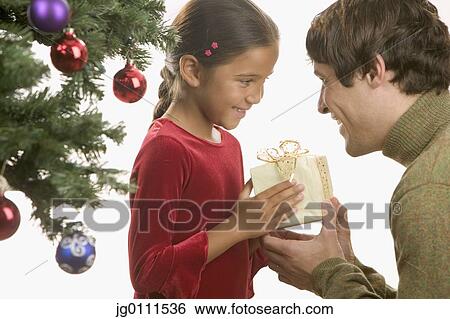 Stock Photograph - Father giving his daughter a Christmas present. Fotosearch