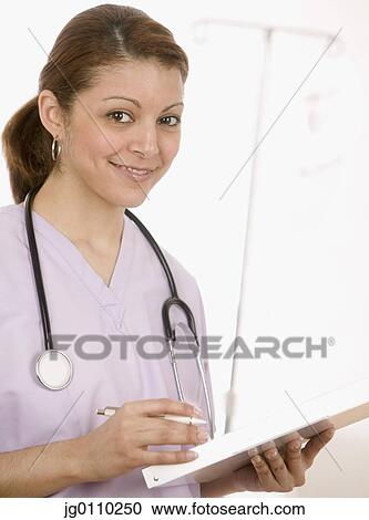 Female nurse holding a clipboard smiling View Large Photo Image Stock Image - Female nurse holding a clipboard smiling. Fotosearch