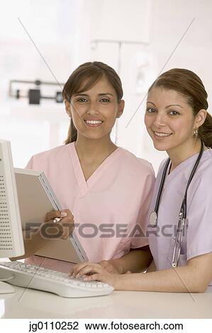 Stock Image - Female nurses standing together smiling. Fotosearch