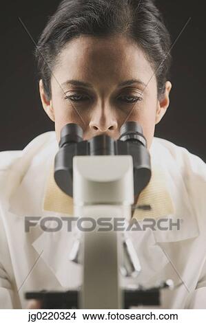 Female scientist looking through a microscope View Large Photo Image Picture - Female scientist looking through a microscope. Fotosearch