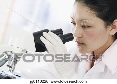 Female scientist looking through a microscope View Large Photo Image Stock Photograph - Female scientist looking through a microscope. Fotosearch