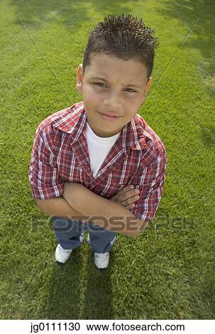 High angle view of a young boy standing on a lawn with his arms folded View Large Photo Image Stock Image - High angle view of a young boy standing on a lawn with his arms folded. Fotosearch