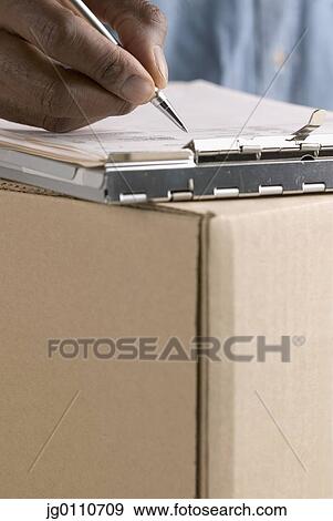 Stock Photo - Human hand holding a pen writing in a clipboard. Fotosearch