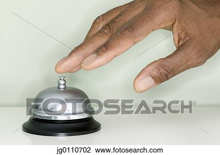 Stock Image - Human hand pressing a desk bell. Fotosearch