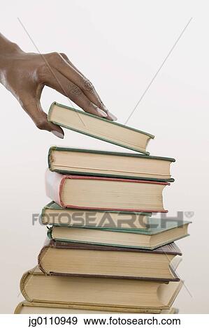 Stock Photo - Human hand taking a book form a heap. Fotosearch