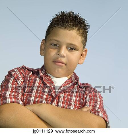 Low angle view of a young boy standing with his arms folded View Large Photo Image Stock Photo - Low angle view of a young boy standing with his arms folded. Fotosearch