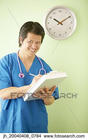 Male doctor smiling writing on a clipboard View Large Photo Image Picture - Male doctor smiling writing on a clipboard. Fotosearch
