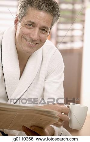 Man sitting holding a coffee cup and a newspaper View Large Photo Image Stock Photograph - Man sitting holding a coffee cup and a newspaper. Fotosearch