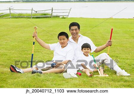 Man with two young boys sitting on a lawn View Large Photo Image Stock Image - Man with two young boys sitting on a lawn. Fotosearch