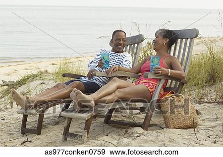 Stock Photo - Mature couple sitting together on easy chairs at the beach. Fotosearch