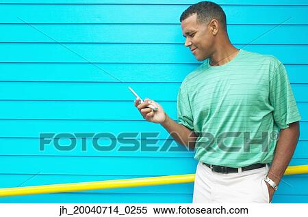 Mid adult man holding a mobile phone View Large Photo Image Stock Photography - Mid adult man holding a mobile phone. Fotosearch