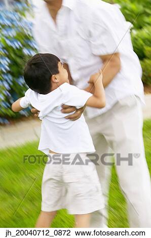 Mid adult man playing with a young boy on a lawn View Large Photo Image Stock Image - Mid adult man playing with a young boy on a lawn. Fotosearch
