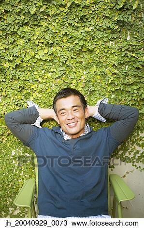 Mid adult man sitting on a chair with his hands behind his head View Large Photo Image Stock Image - Mid adult man sitting on a chair with his hands behind his head. Fotosearch
