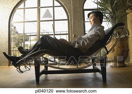 Mid adult man sitting on a relaxing chair View Large Photo Image Stock Image - Mid adult man sitting on a relaxing chair. Fotosearch