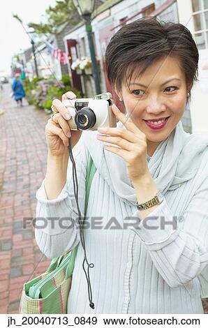 Mid adult woman holding a camera View Large Photo Image Stock Photo - Mid adult woman holding a camera. Fotosearch