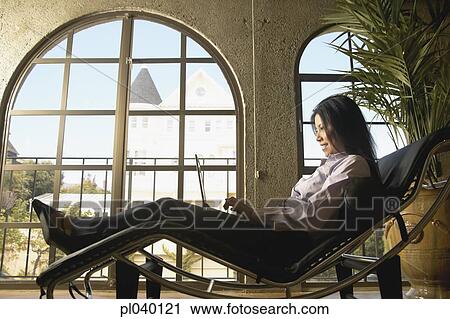 Mid adult woman sitting on a relaxing chair View Large Photo Image Stock Image - Mid adult woman sitting on a relaxing chair. Fotosearch