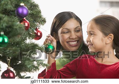 Mother and daughter decorating a Christmas tree View Large Photo Image Stock Image - Mother and daughter decorating a Christmas tree. Fotosearch