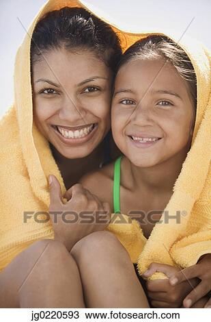 Stock Image - Mother and daughter sitting together wrapped in a towel. Fotosearch