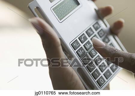 Stock Photography - Person's hands operating a calculator. Fotosearch