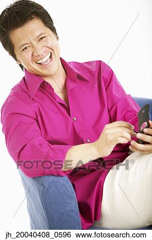 Portrait of a adult man sitting holding a hand held device smiling View Large Photo Image Stock Photograph - Portrait of a adult man sitting holding a hand held device smiling. Fotosearch