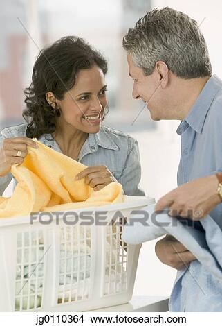 Portrait of a couple folding clothes from a laundry basket View Large Photo Image Picture - Portrait of a couple folding clothes from a laundry basket. Fotosearch