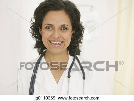 Portrait of a female doctor with a stethoscope around her neck looking at camera smiling View Large Photo Image Stock Photo - Portrait of a female doctor with a stethoscope around her neck looking at camera smiling. Fotosearch