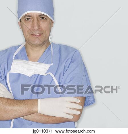 Stock Image - Portrait of a male doctor in full scrubs looking at camera. Fotosearch