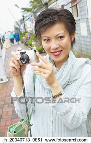 Portrait of a mid adult woman holding a camera View Large Photo Image Stock Image - Portrait of a mid adult woman holding a camera. Fotosearch