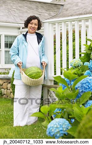 Portrait of a mid adult woman standing in a garden View Large Photo Image Stock Image - Portrait of a mid adult woman standing in a garden. Fotosearch