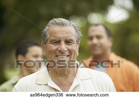 Stock Photograph - Portrait of a senior man smiling with his son and grandson behind. Fotosearch