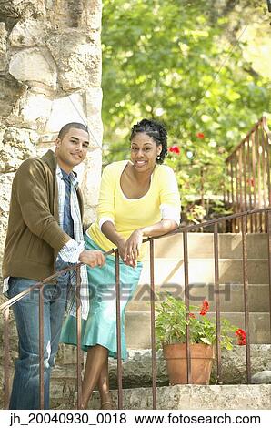 Portrait of a young couple standing together leaning on a railing View Large Photo Image Stock Photo - Portrait of a young couple standing together leaning on a railing. Fotosearch