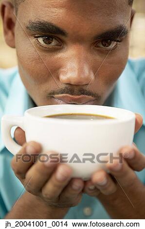 Portrait of a young man holding a cup of coffee View Large Photo Image Picture - Portrait of a young man holding a cup of coffee. Fotosearch