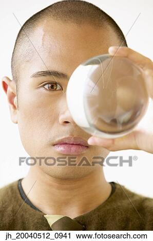Portrait of a young man holding a crystal ball up to his eye View Large Photo Image Stock Image - Portrait of a young man holding a crystal ball up to his eye. Fotosearch