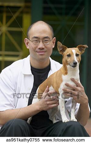 Portrait of a young man sitting holding a dog View Large Photo Image Stock Photography - Portrait of a young man sitting holding a dog. Fotosearch
