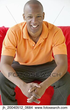 Portrait of a young man sitting on a couch smiling View Large Photo Image Picture - Portrait of a young man sitting on a couch smiling. Fotosearch