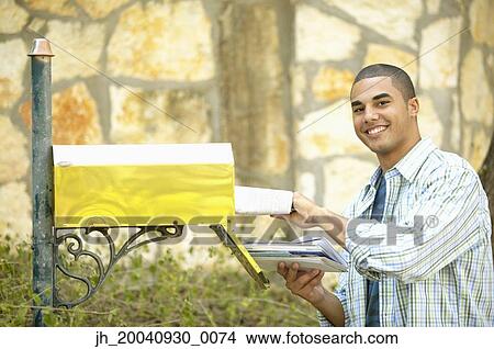 Portrait of a young man taking out mail from a mail box View Large Photo Image Picture - Portrait of a young man taking out mail from a mail box. Fotosearch