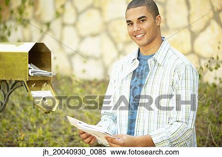 Portrait of a young man taking out mail from a mail box View Large Photo Image Stock Photography - Portrait of a young man taking out mail from a mail box. Fotosearch