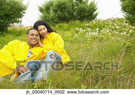 Stock Image - Portrait of a young woman and a mid adult man sitting together outdoors. Fotosearch