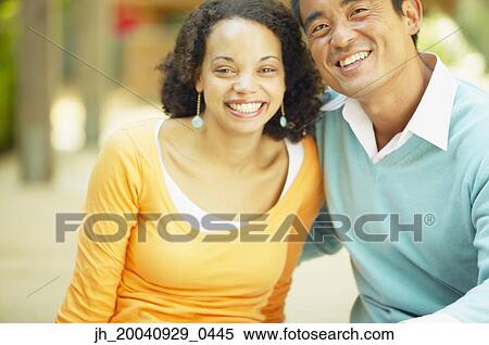 Portrait of a young woman and a mid adult man sitting together holding each other View Large Photo Image Stock Photography - Portrait of a young woman and a mid adult man sitting together holding each other. Fotosearch