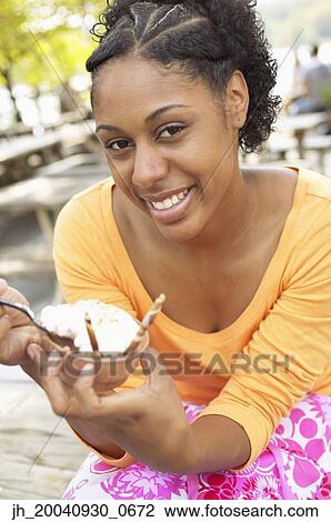 Portrait of a young woman eating an ice cream View Large Photo Image Stock Image - Portrait of a young woman eating an ice cream. Fotosearch