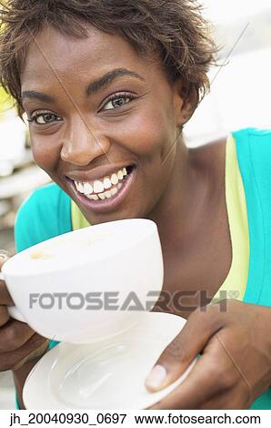 Portrait of a young woman holding a cup of coffee View Large Photo Image Stock Photo - Portrait of a young woman holding a cup of coffee. Fotosearch
